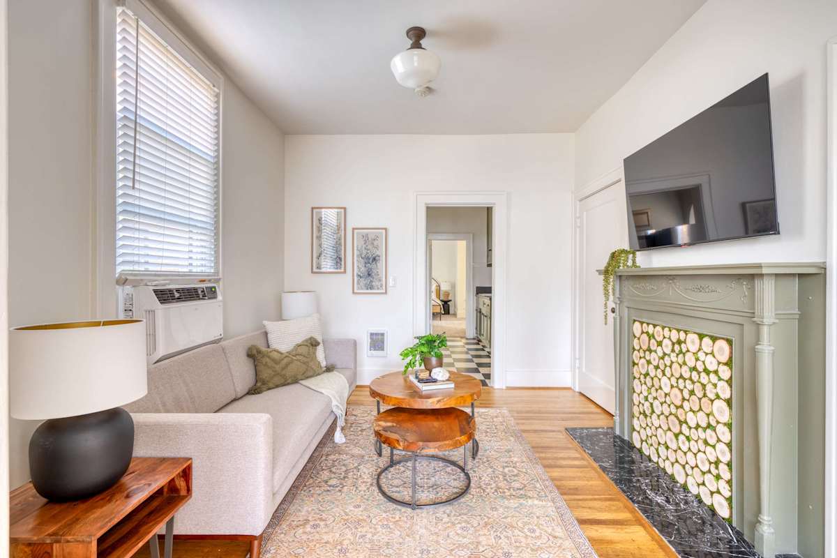A charming apartment living room with decorative fireplace, live-edge coffee table, and hardwood floors near Hawthorne