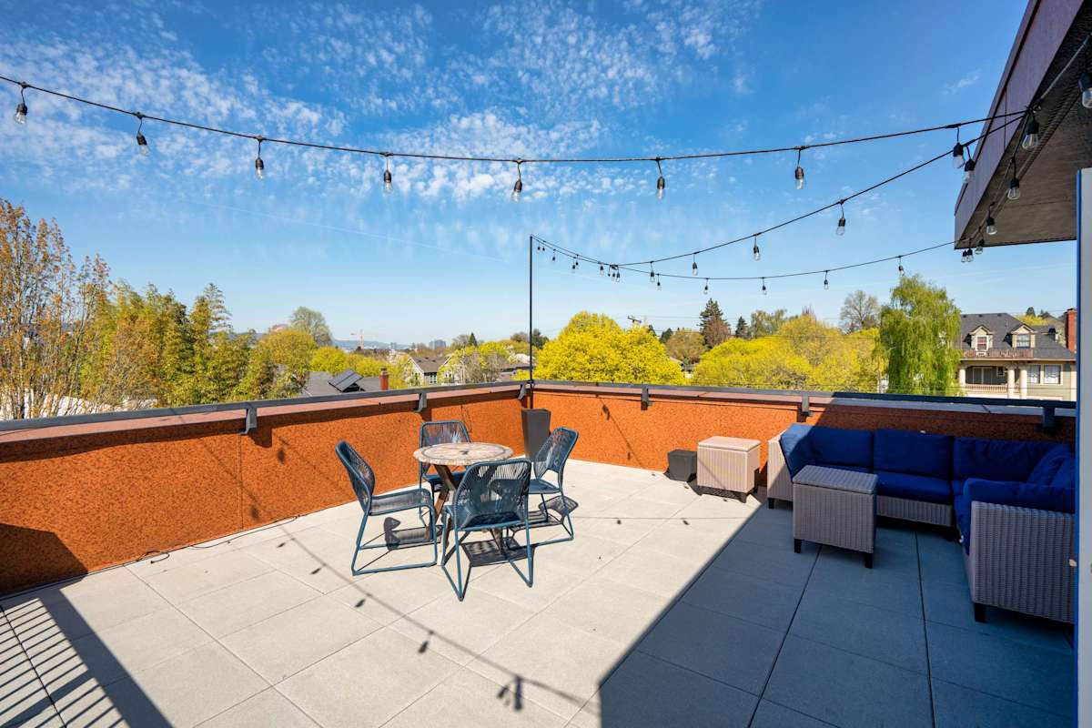 A private rooftop terrace with string lights, outdoor dining, and neighborhood views