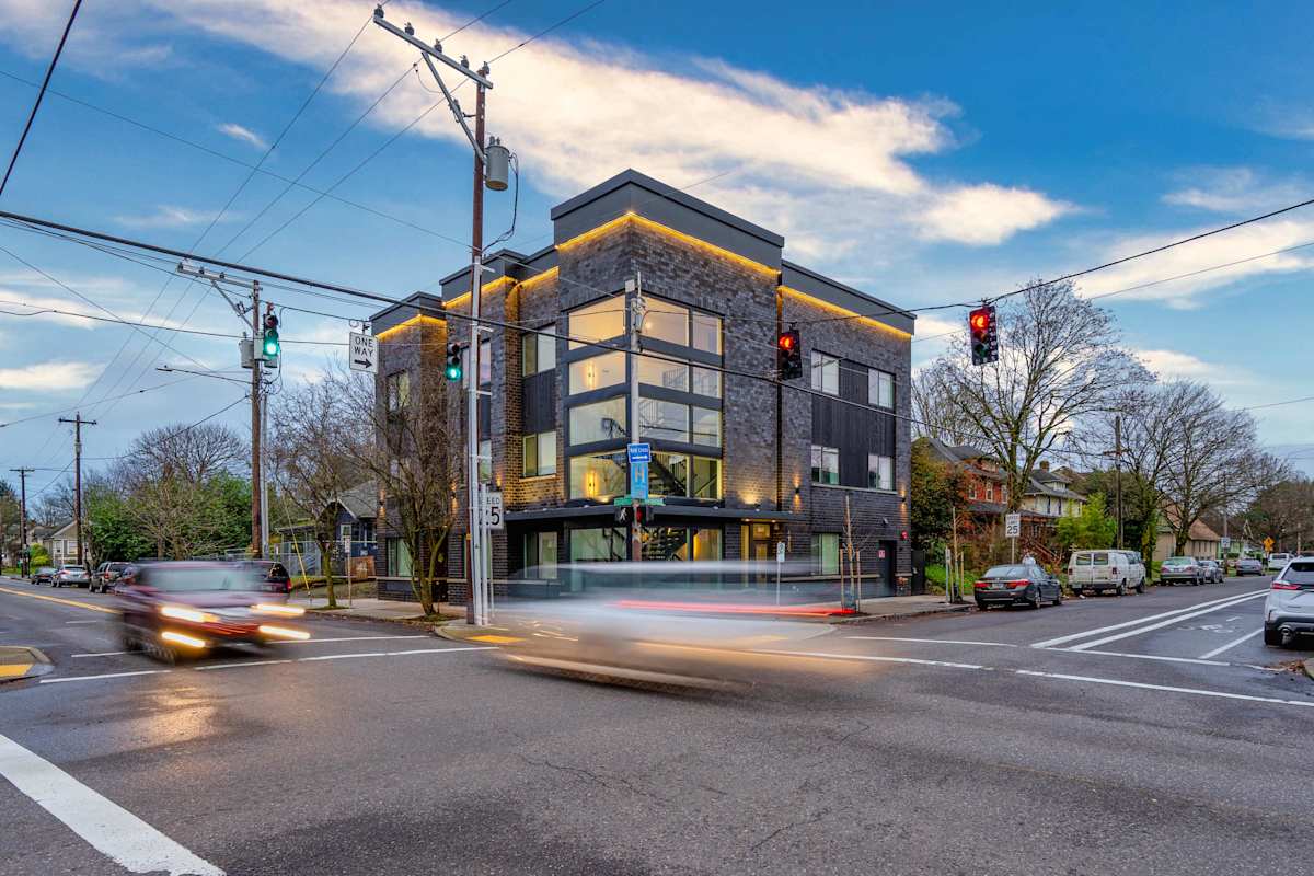 The Vancouver building — a modern apartment building with stone facade and accent lighting at dusk in Portland