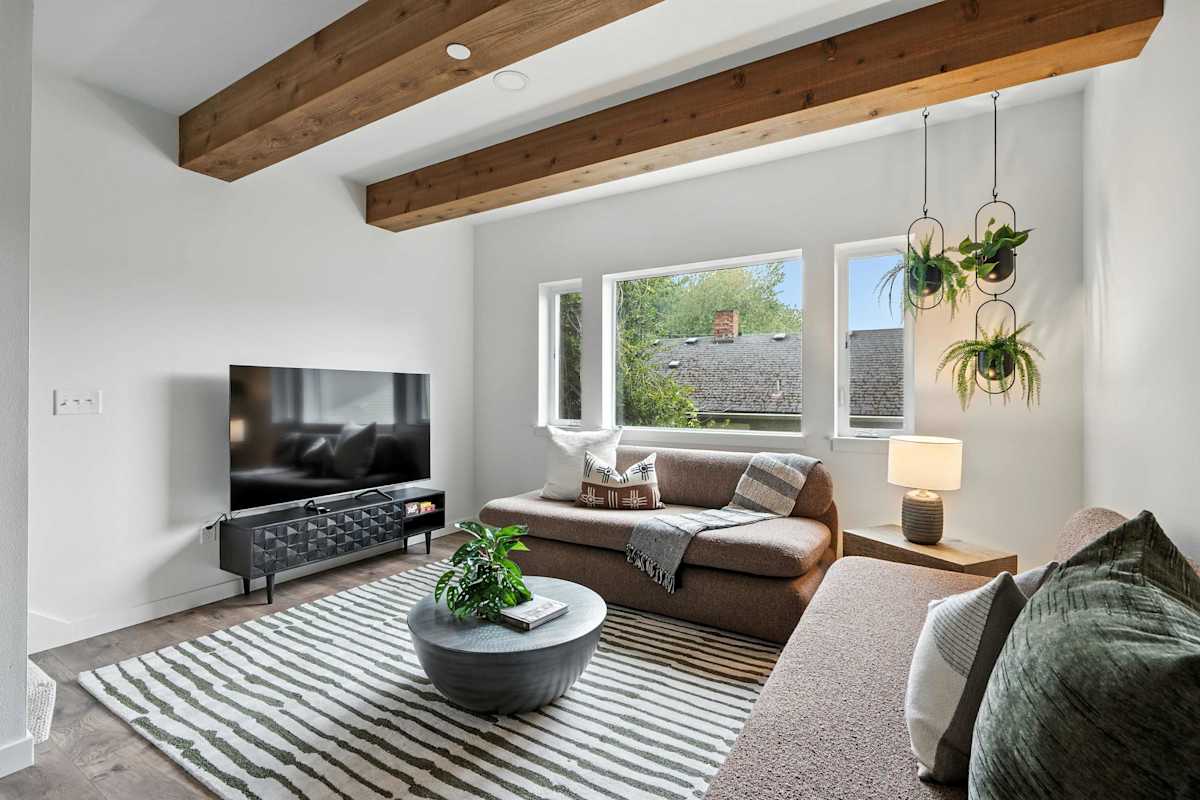 A designer dining room with wood beams, dome pendant lights, and open living area in a Portland vacation home