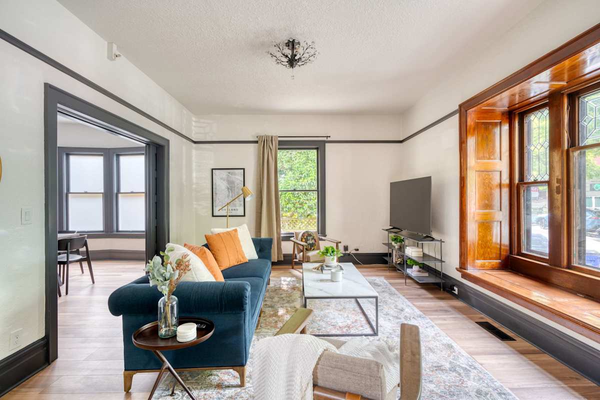 Living room with exposed wood beams, hanging plants, and natural light in a Portland vacation home