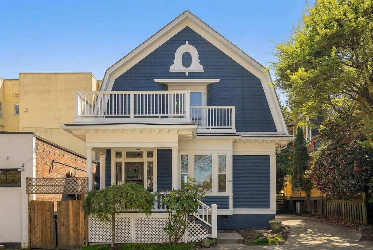 A blue Victorian home with gambrel roof and upper balcony on NW Kearney in Portland